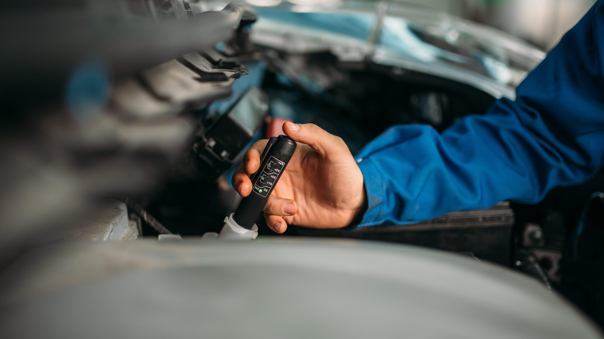 Male technician checks brake fluid level in car - JC Whitney