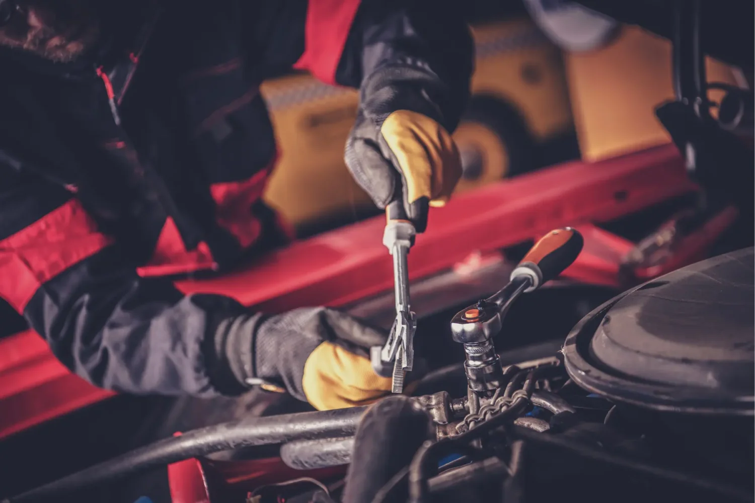 A Beginners Guide to Restoring Classic Cars 1 - JC Whitney Mechanic using tools to perform engine repairs on a red car in a workshop