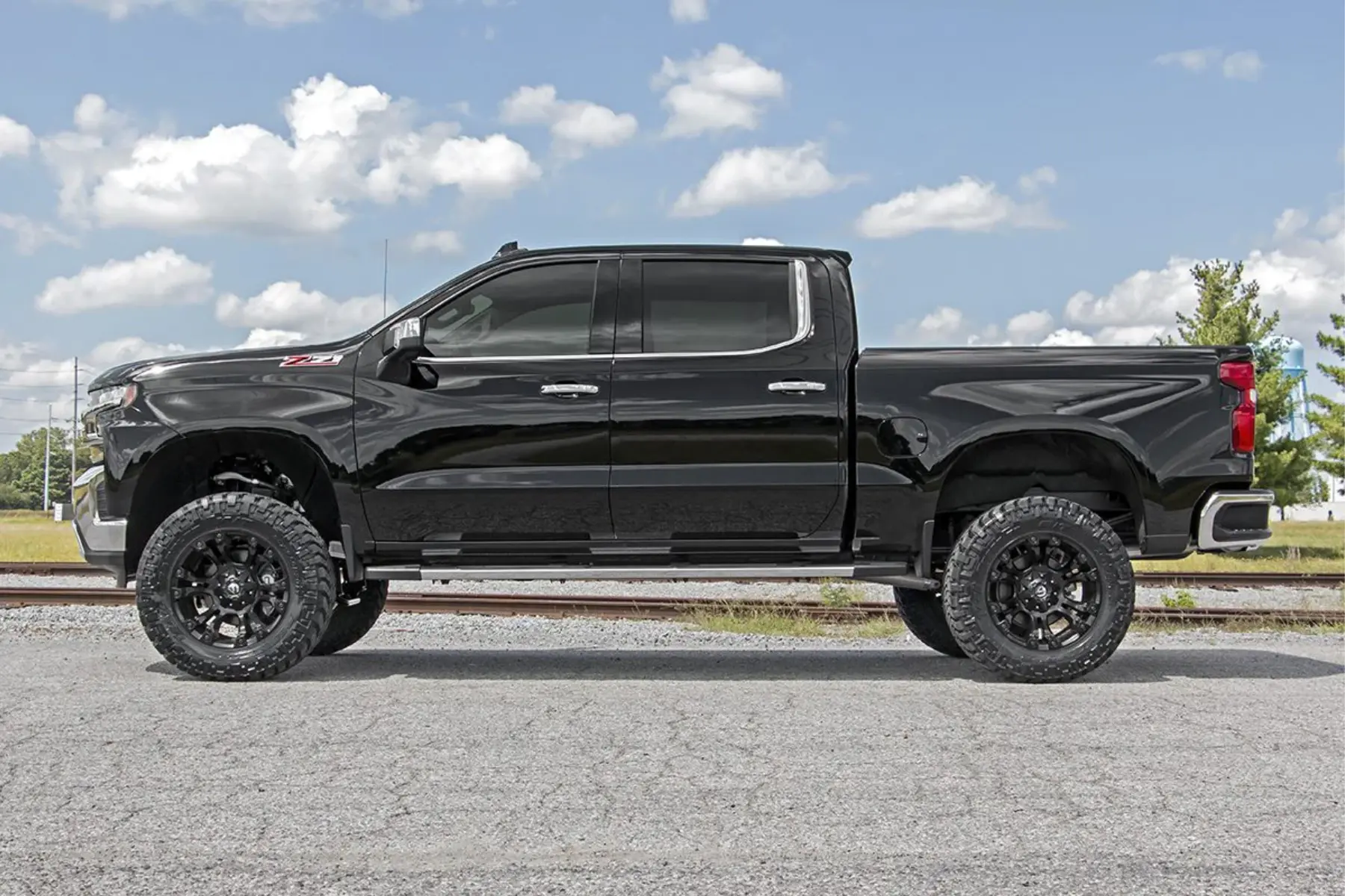Side view of a black Chevy Silverado with noticeable suspension modifications and lifted stance.