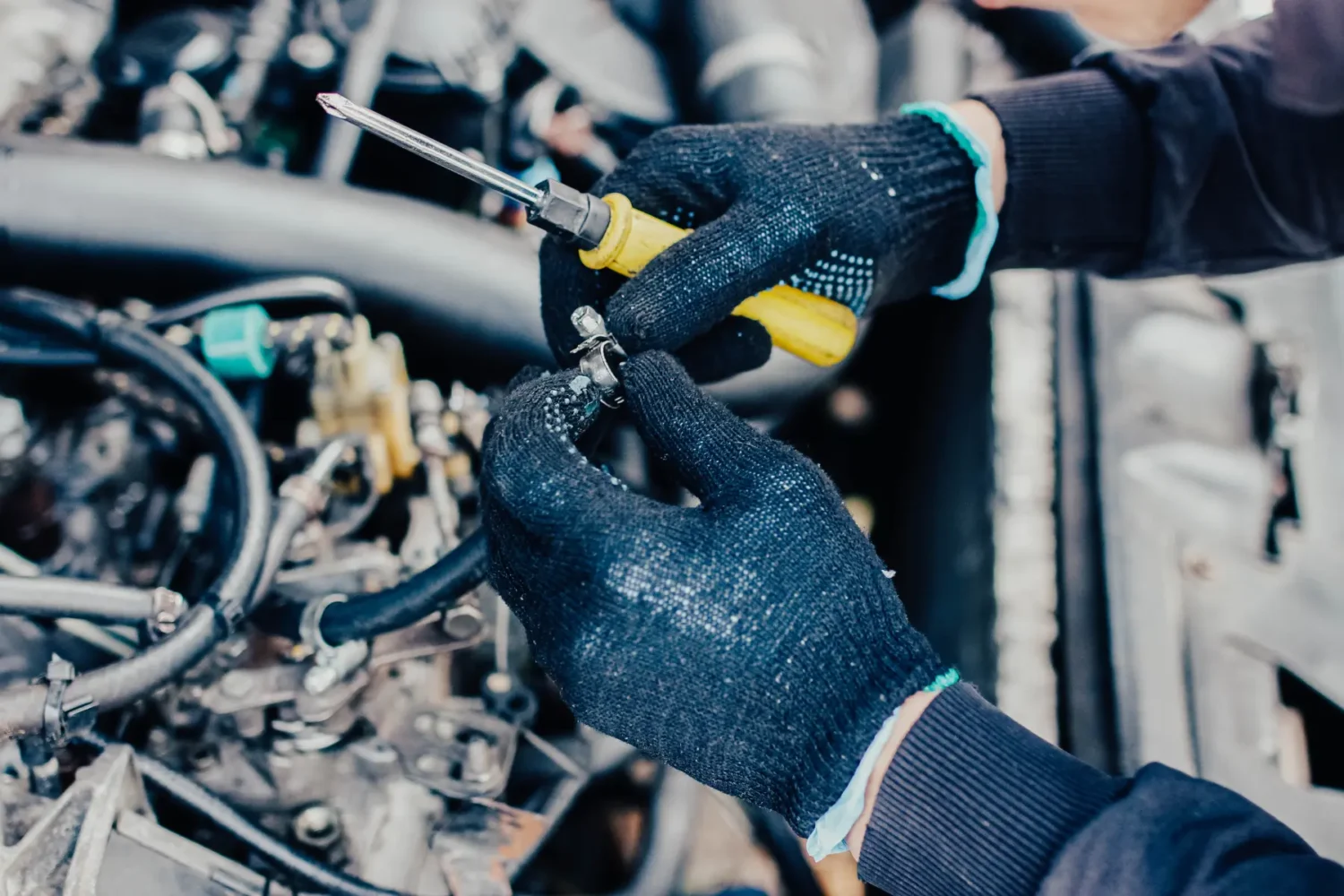 Fuel and Air System Maintenance - JC Whitney Fuel and air system maintenance with a mechanic adjusting a hose clamp under the hood.
