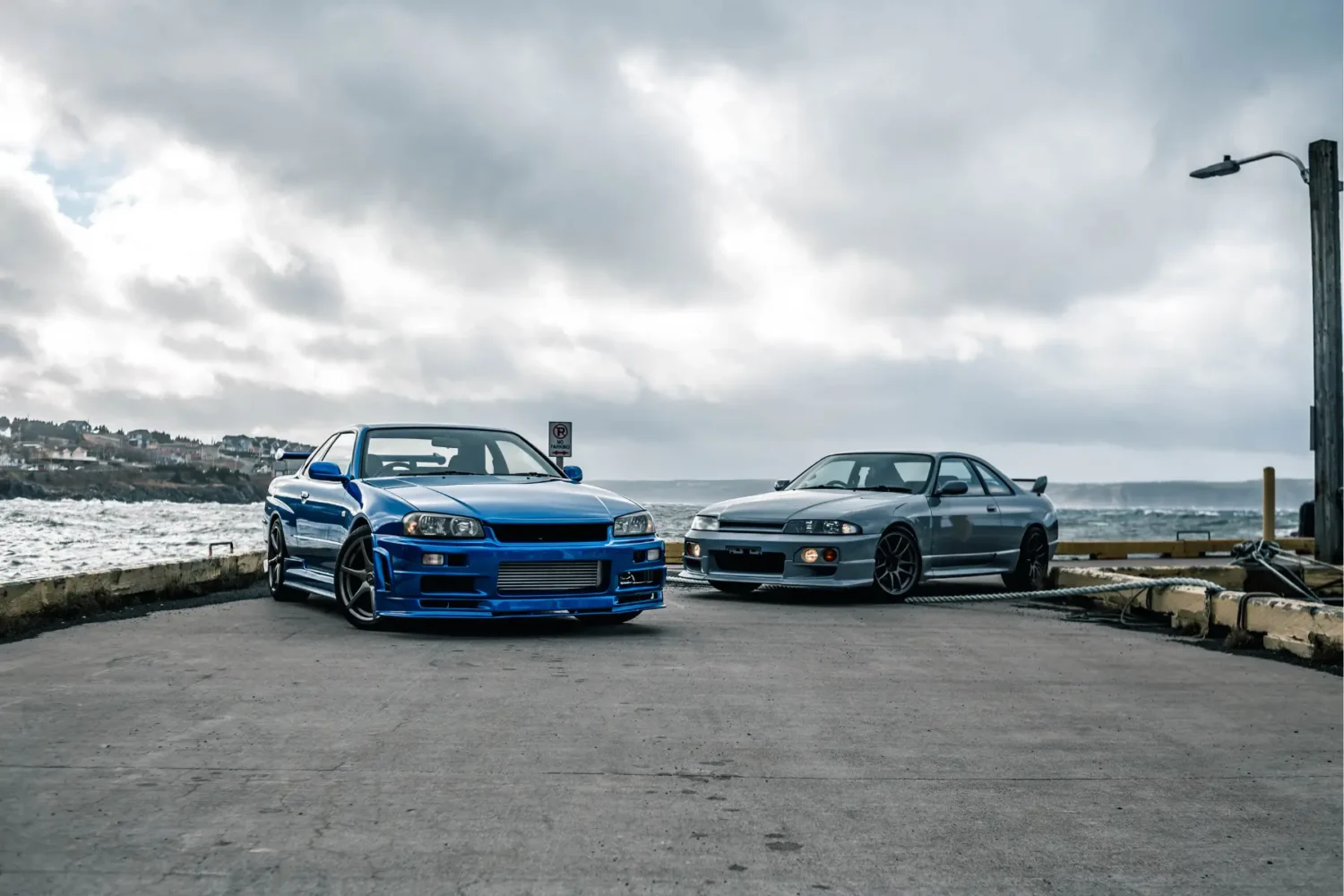 car customization - JC Whitney Car customization on two modified Nissan Skylines parked near the ocean.