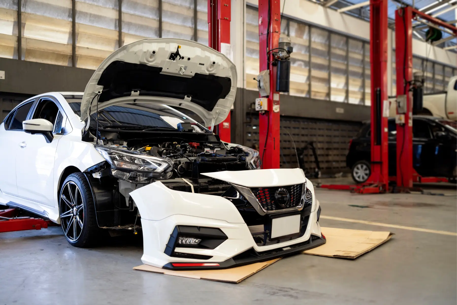 Creative car customization shown on a Nissan with front bumper removed for repairs in a garage.