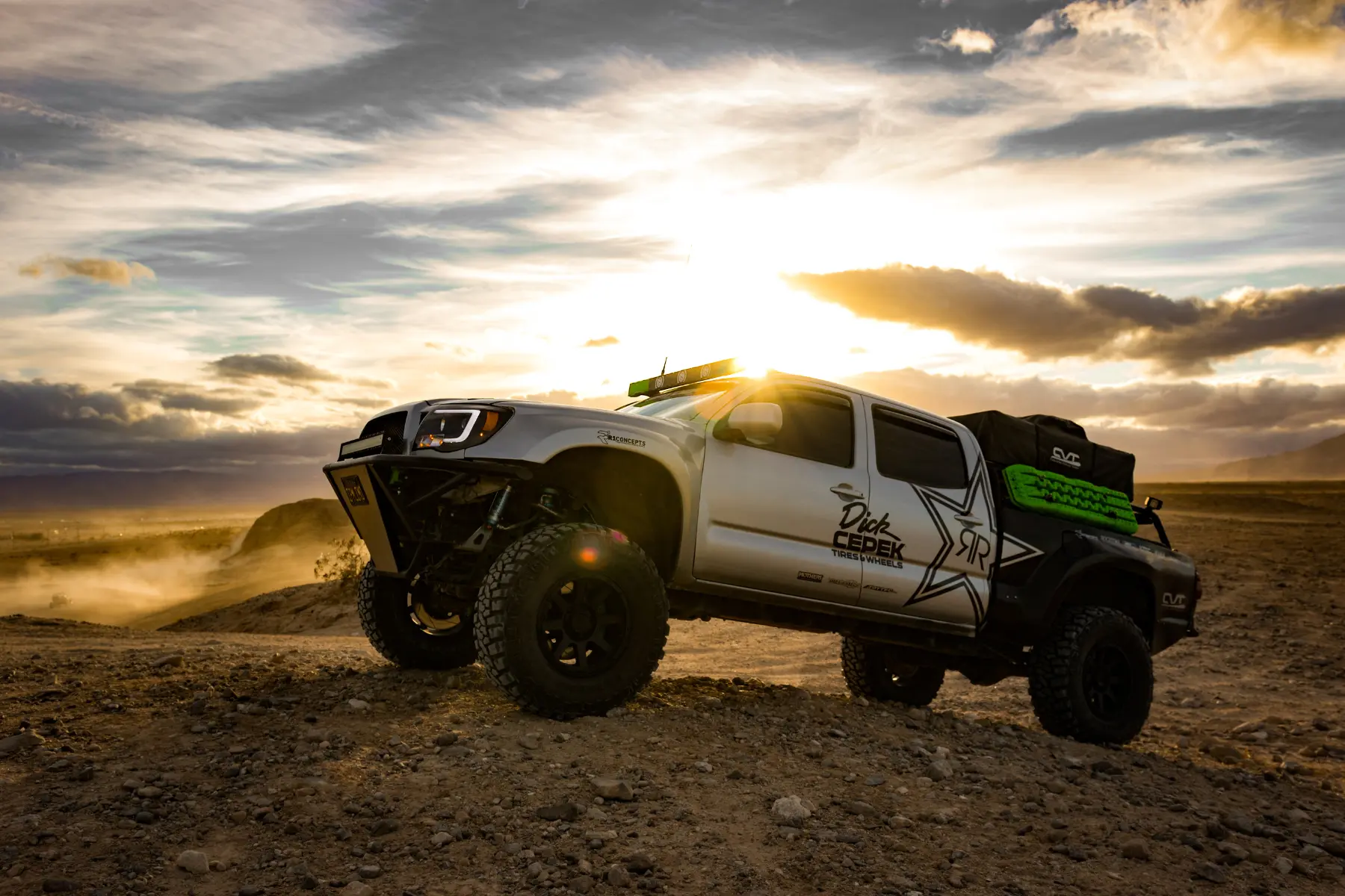 Truck suspension upgrades featured on a lifted off-road truck at sunset in the desert.