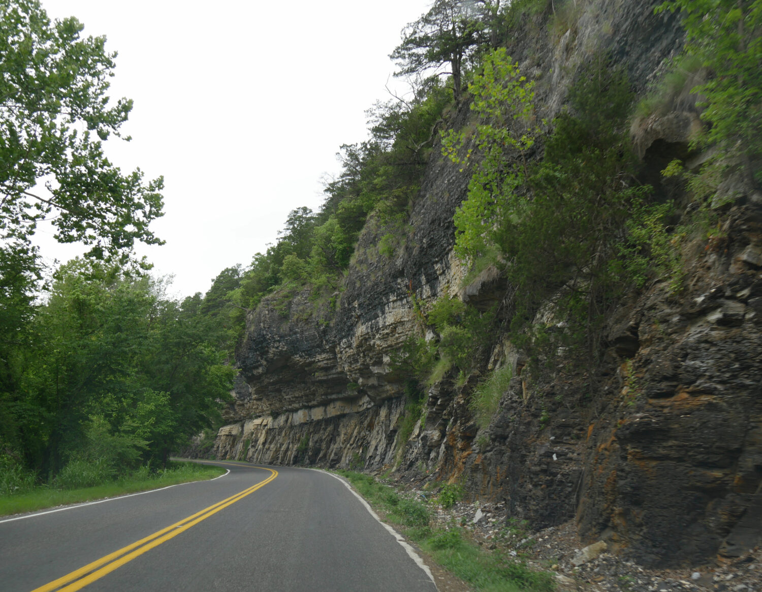 Scenic winding road with a solid rock wall at the foothills of Ozard Mountains in Oklahoma - JC Whitney