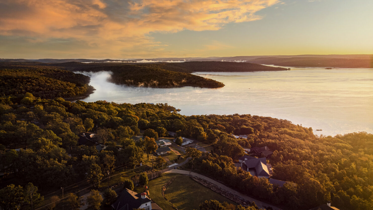 Sunset sky over the Tenkiller lake Oklah and green forested area in the evening - JC Whitney