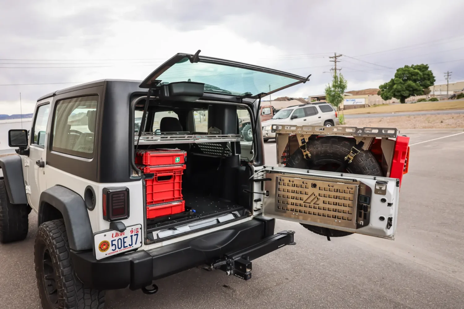 Jeep Storage Solutions - JC Whitney Jeep storage solutions with red gear boxes and mounted spare tire in an organized rear cargo setup.