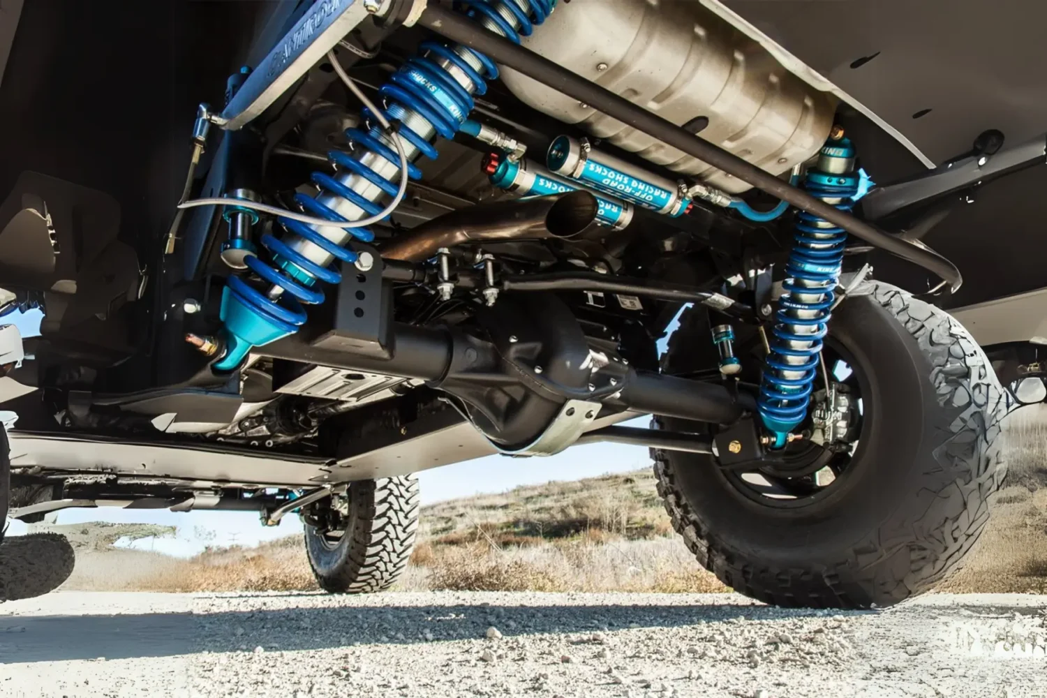 Jeep Suspension Upgrades - JC Whitney Jeep suspension upgrades featuring heavy-duty blue coilover shocks and off-road components installed underneath.