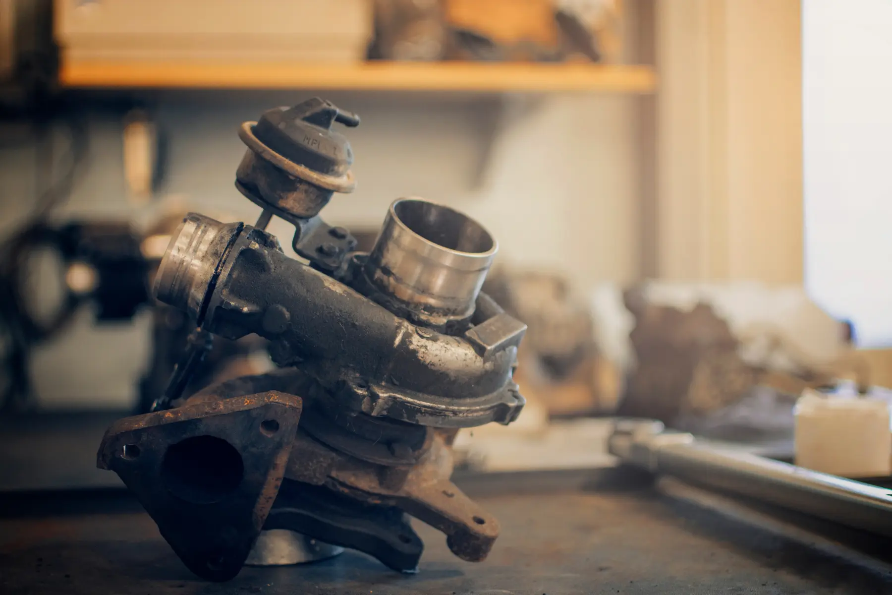 Superchargers vs. turbochargers comparison showing a worn turbocharger on a workshop bench.