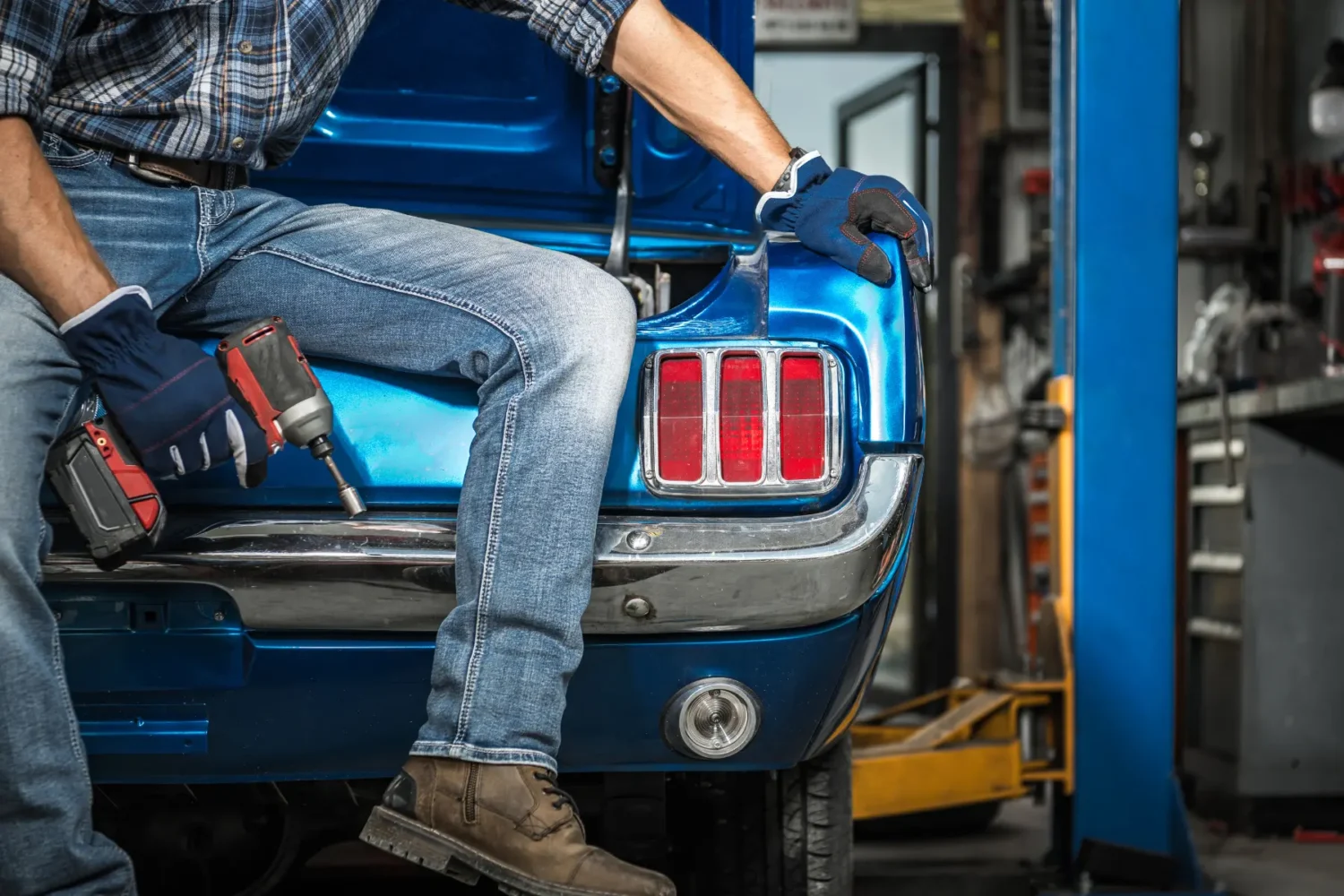 Vintage Car Parts - JC Whitney Vintage car parts technician sitting on a blue classic car with a power tool in hand.