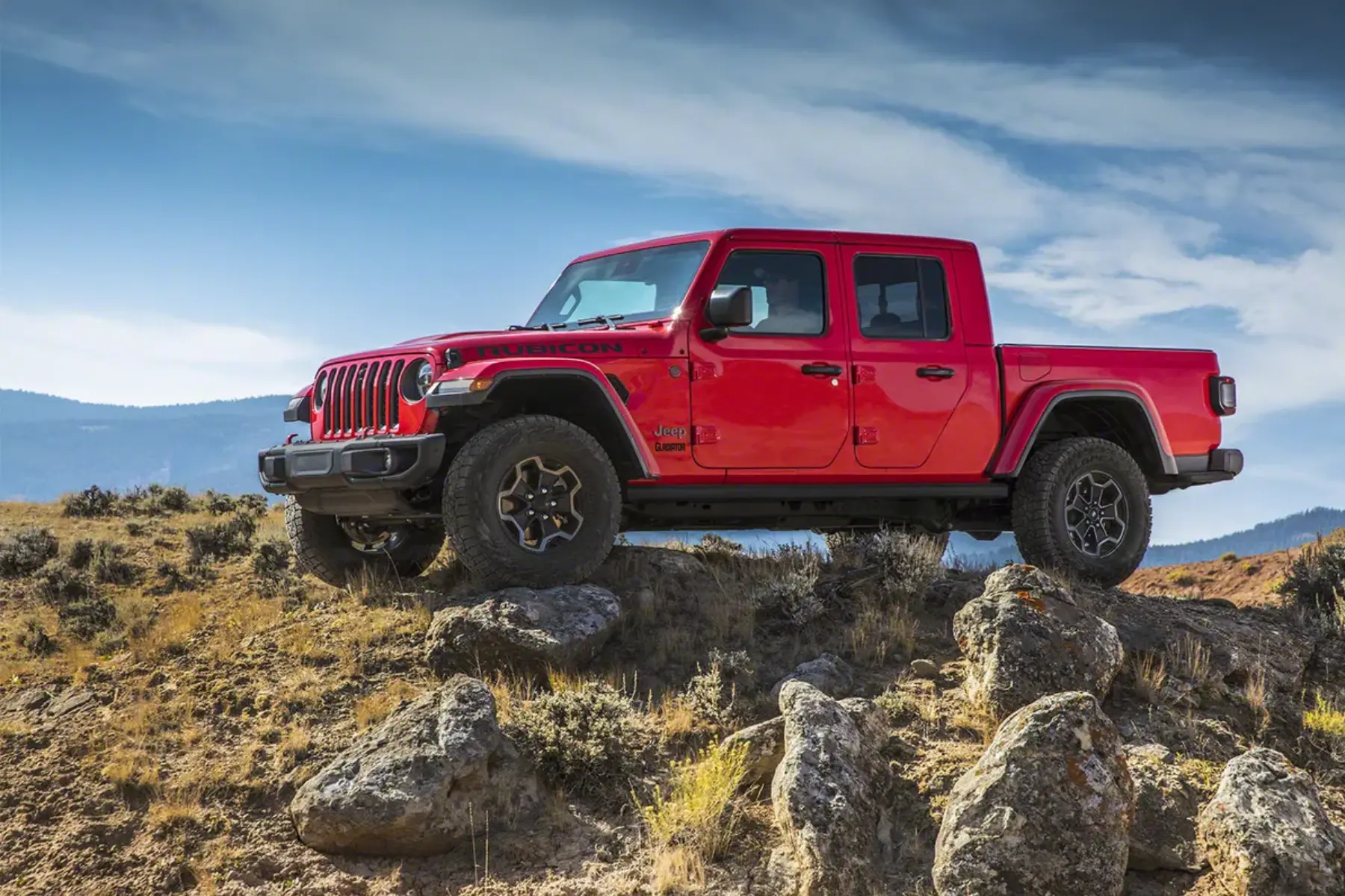 jeep gladiator - JC Whitney Jeep Gladiator Rubicon parked on rocky terrain during an off-road adventure under a clear blue sky.