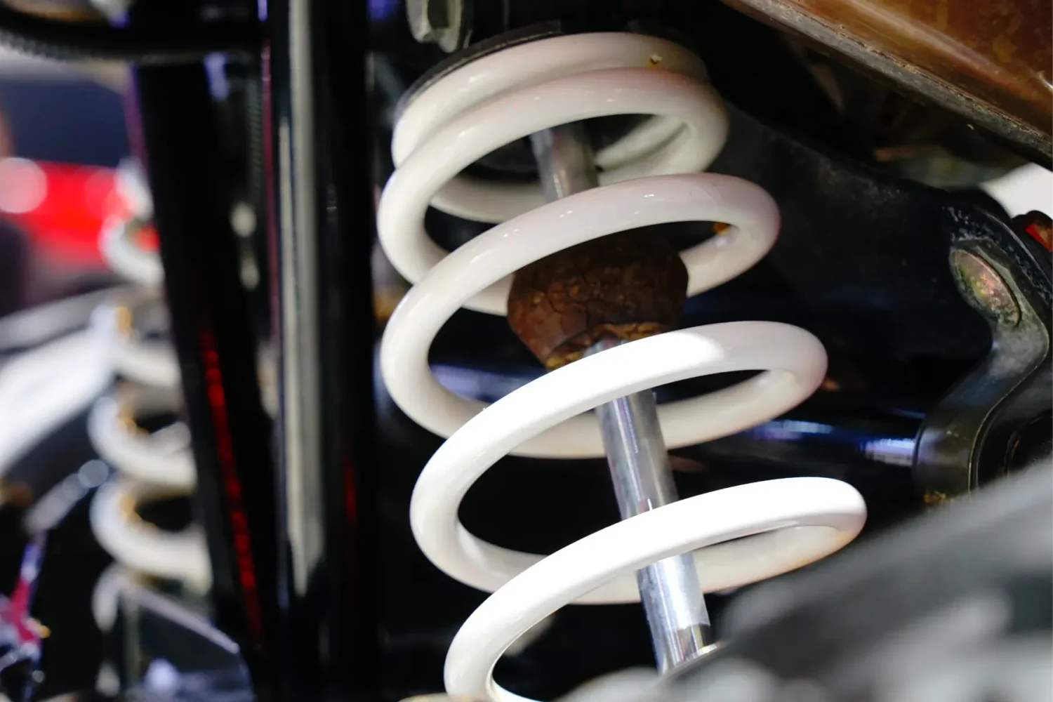 leaf spring upgrades - JC Whitney Leaf spring upgrades featuring close-up of a coiled suspension system with visible rust on the shock.