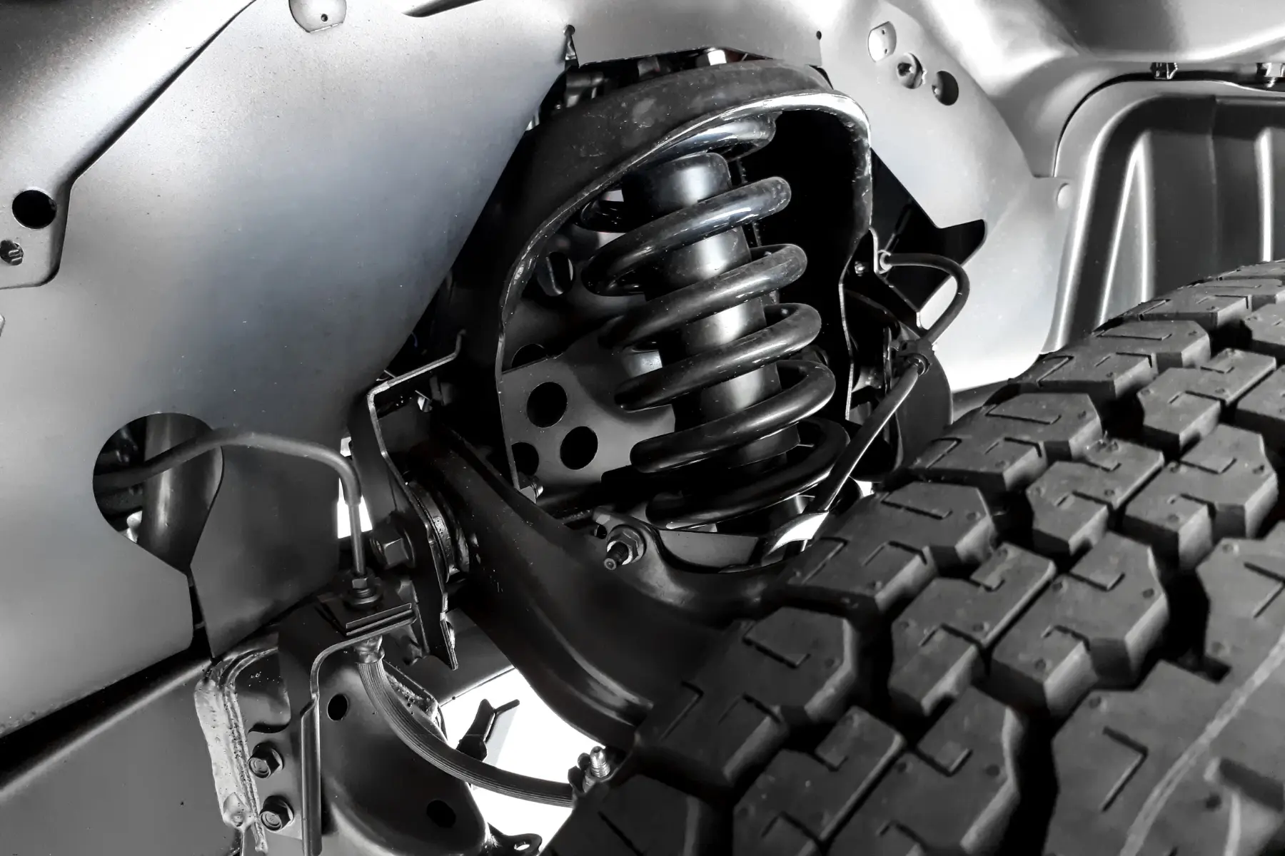 Truck spring replacement showing new coil spring and suspension components near rear tire